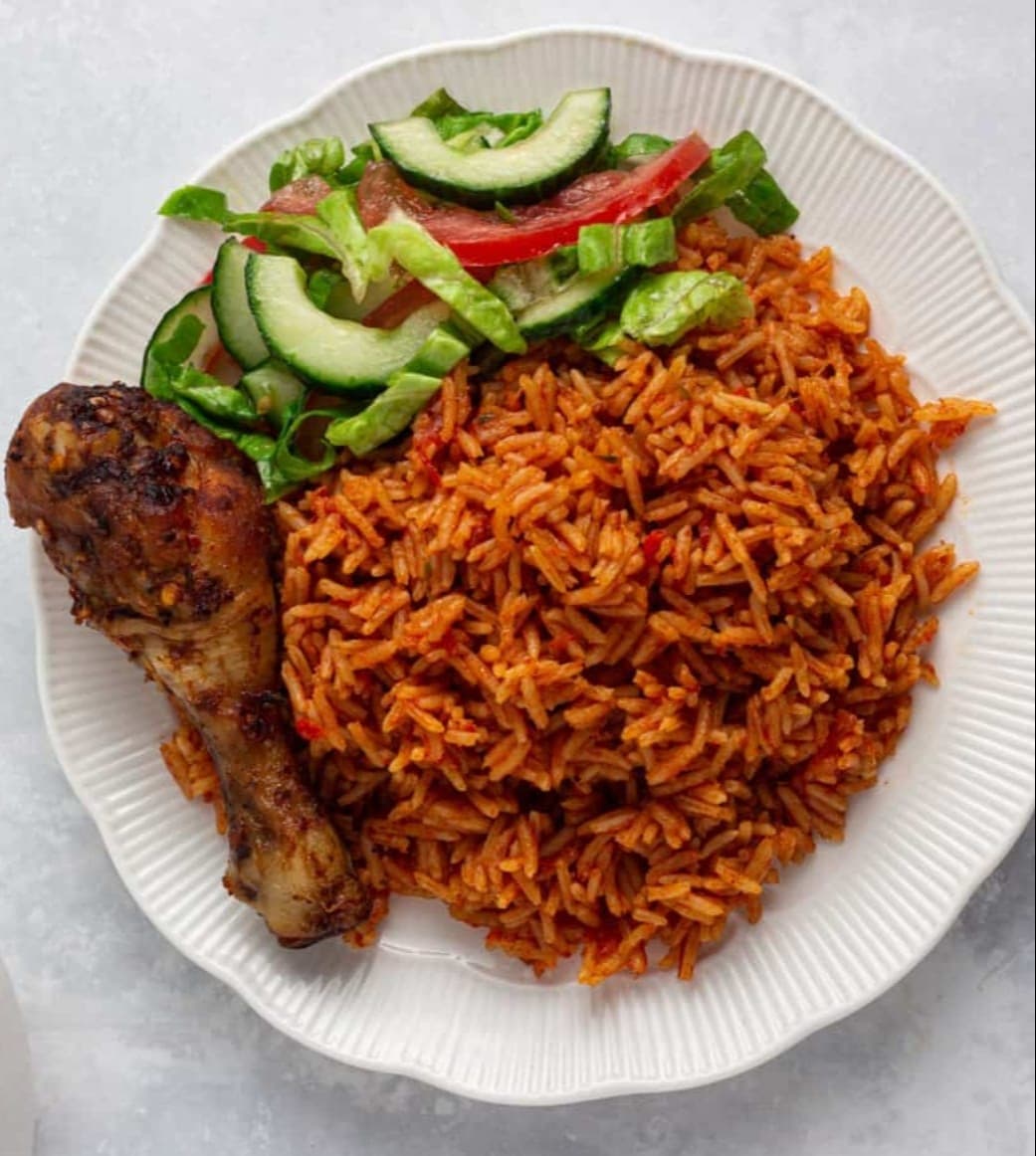 A plate of jollof rice with chicken and fresh vegetables